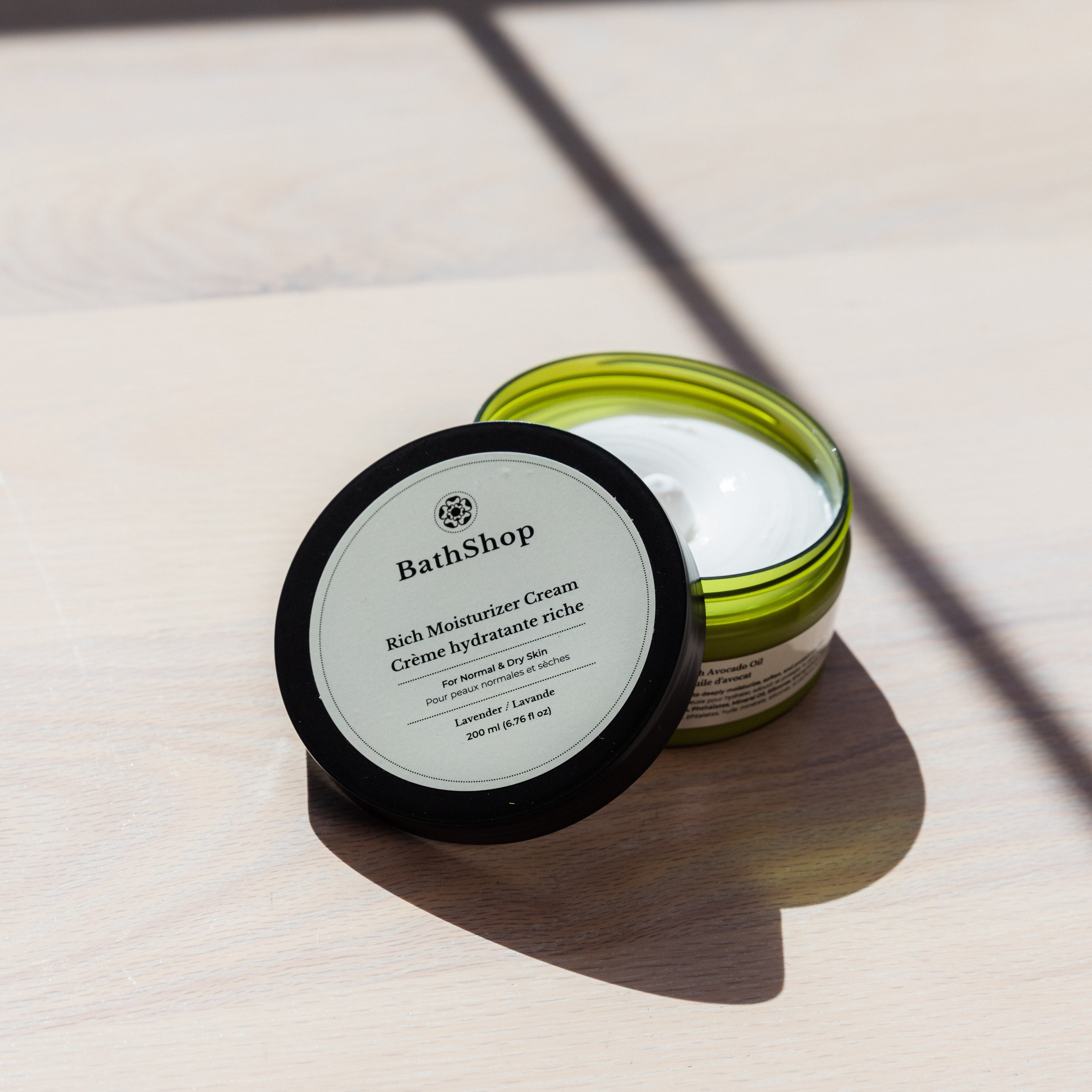 Jar of The Bath Shop rich moisturizer cream on a light surface with shadows